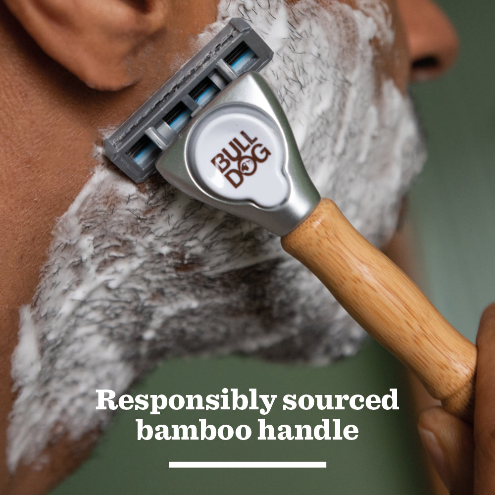 A close-up of someone shaving with the Original Bamboo Razor, featuring tempered steel blades and a handle made from responsibly sourced bamboo. The face is covered in shaving cream, with text reading: Responsibly sourced bamboo handle.