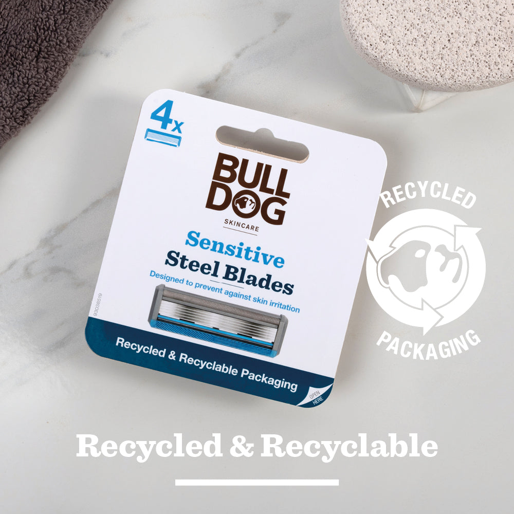A pack of Sensitive Steel Blades with “Recycled & Recyclable Packaging” and a recycling symbol, shown on a white background beside a towel and pumice stone—ideal replacement blades for your Bulldog Razor.