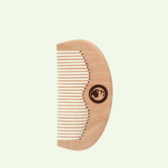The Beard Comb is a light wooden comb with evenly spaced teeth and a rounded handle featuring a dark circular logo of a stylized dog and cat. Set against a pale background, it pairs perfectly with Original Beard Oil and other beard products.