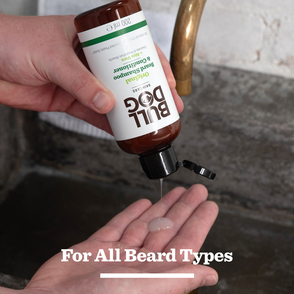 A person pours the Original Beard Care Kit shampoo and conditioner into their hand over a sink, with "For All Beard Types" at the bottom. It's the perfect addition to any beard grooming kit.