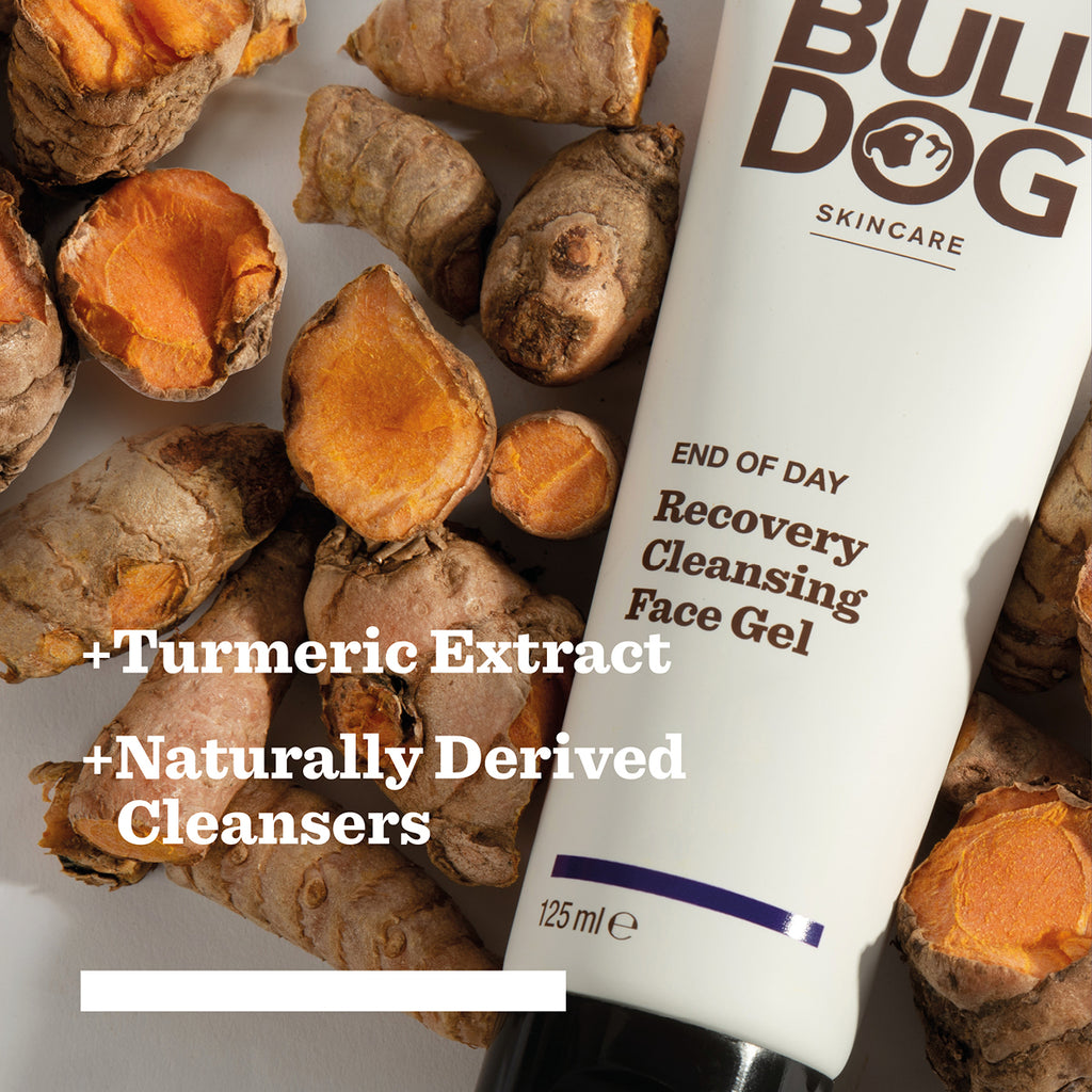 A tube of Bulldog Skincare from the End of Day Collection Bundle rests among turmeric roots, highlighting “+ Turmeric Extract,” “+ Naturally Derived Cleansers,” and its natural origin ingredients.