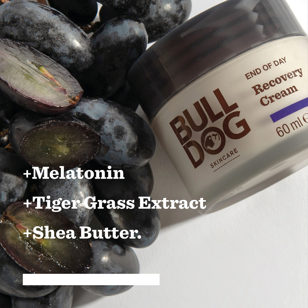 A jar from the End of Day Collection Bundle sits beside a bunch of black grapes. Text highlights its natural origin ingredients: Melatonin, Tiger Grass Extract, and Shea Butter.